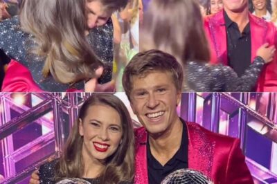 “YOU ARE MY HERO.” Those were the first words Robert Irwin whispered as he wrapped his arms around his big sister, Bindi, moments after being crowned the Season 34 champion of Dancing with the Stars. And in that instant, the ballroom shifted — from celebration to something far more intimate, emotional, and unforgettable. Confetti was still drifting through the air when Robert pulled Bindi close, his voice trembling with the weight of everything their family had lived through. Bindi, already fighting tears, cupped his face and whispered back, “No, Robbie… you did this. Dad would be so proud.” The camera caught it all — the rawness, the love, the history between two siblings who grew up carrying a legacy far bigger than themselves.  Terri Irwin stood just a few steps away, her hands covering her mouth as she cried — not with sadness, but with overwhelming pride. It wasn’t just a victory for Robert; it was a full-circle  for the entire Irwin family. Ten years earlier, Bindi had claimed her own Mirrorball trophy. Now, watching her little brother rise to the same height, with the same heart, was almost too much for her to bear. Back on the dance floor, Robert held the Mirrorball against his chest like it was made of memories — his father’s laugh, his mother’s strength, his sister’s guidance. When the crowd rose to their feet, cheering, it wasn’t for the choreography. It was for the boy who grew into a man right before their eyes, honoring his family with every step. And in that one hug, one whispered sentence — “You are my hero” — the world witnessed a story of love, legacy, and healing that will be remembered long after the spotlight fades.
